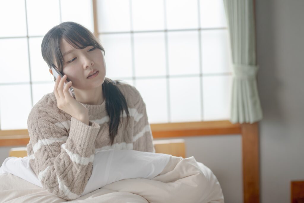 辛そうに電話をかけている女性