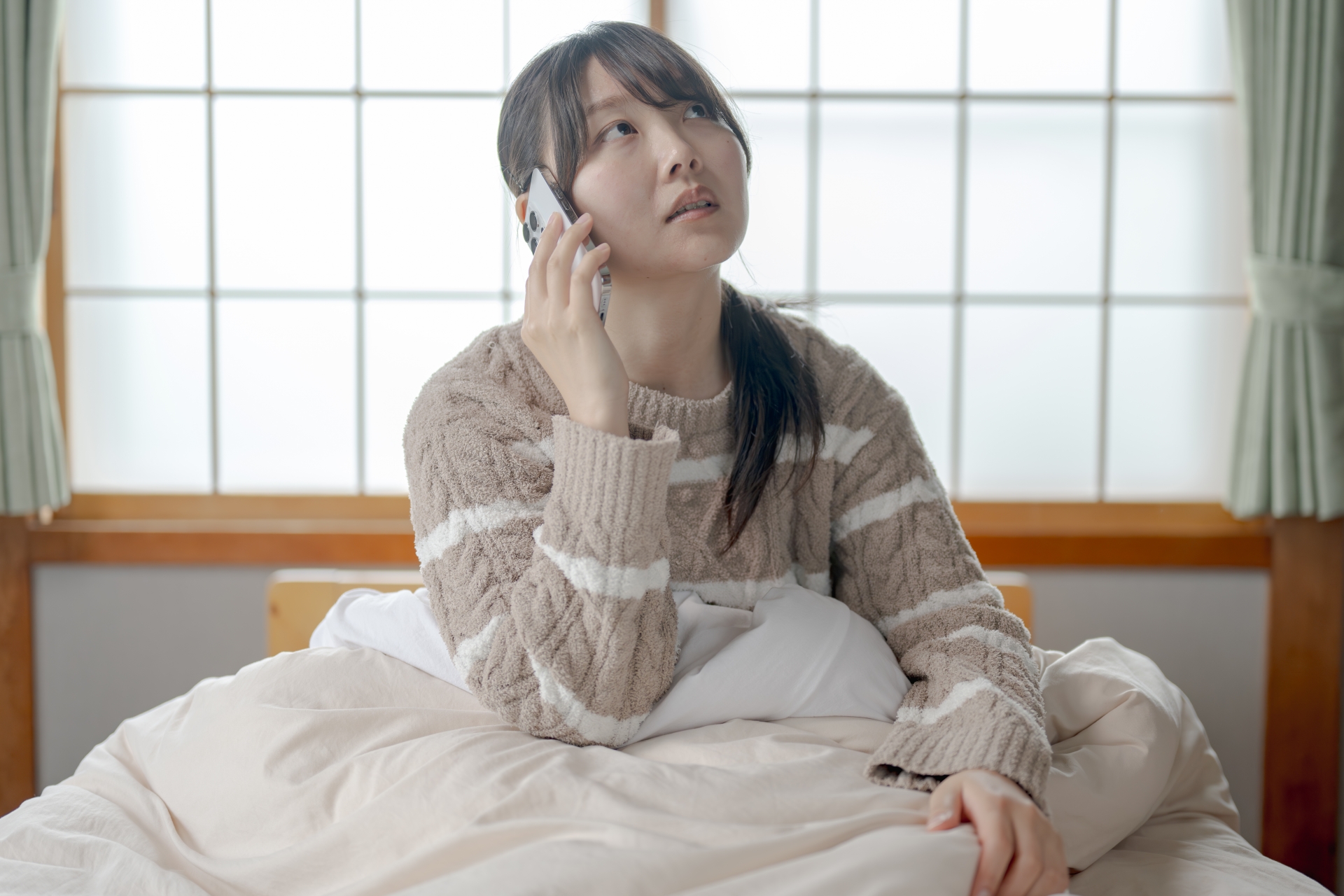 ズル休みの電話をする若い女性