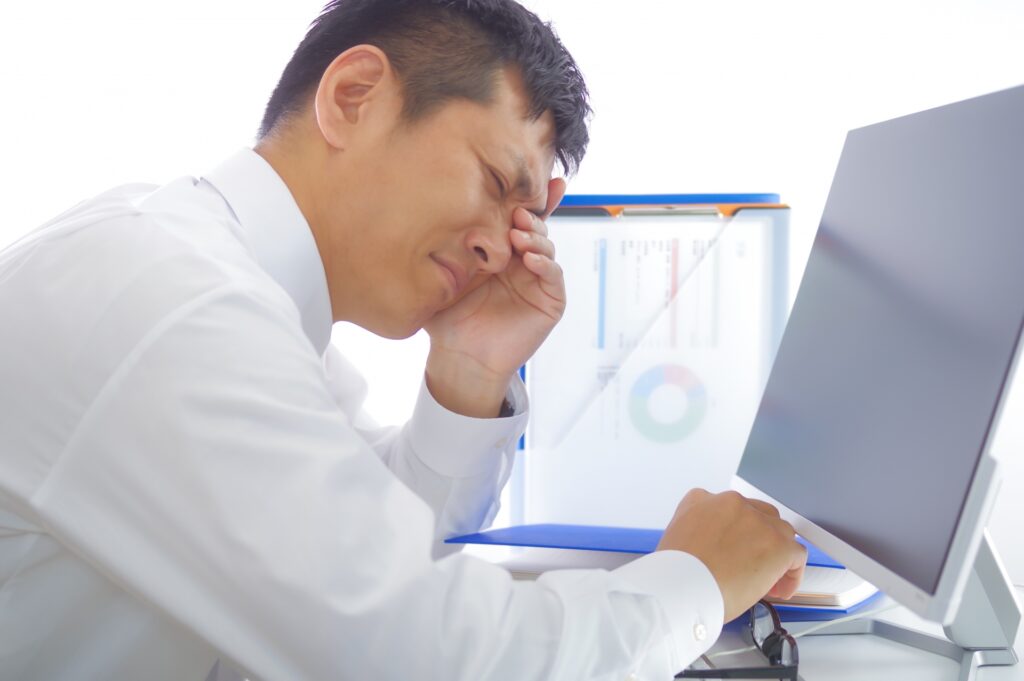 長時間のパソコン作業で疲れている男性